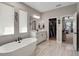 Sunlit bathroom with a modern soaking tub, white cabinetry, and a view of the bedroom and walk-in closet at 3332 Lone Cypress Pt, Oviedo, FL 32765