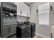 Efficient laundry room with modern black appliances, plenty of cabinet space, and a convenient laundry rack at 3332 Lone Cypress Pt, Oviedo, FL 32765