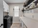 Functional laundry room with white cabinets, shelving, and modern black washer and dryer at 3332 Lone Cypress Pt, Oviedo, FL 32765