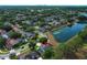 A neighborhood aerial view showcases a pond and homes, some with private pools, surrounded by mature trees and lush landscaping at 3562 Gatlin Pl, Orlando, FL 32812