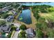 A neighborhood aerial view features a pond surrounded by well-maintained homes and lush trees on a sunny day at 3562 Gatlin Pl, Orlando, FL 32812