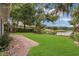 Scenic backyard with a well-kept lawn, brick patio, mature trees, and lake view at 3605 Pershing Ave, Orlando, FL 32812