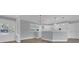 Open-concept living room with hardwood floors leads to a kitchen with white cabinets and modern lighting fixtures at 3605 Pershing Ave, Orlando, FL 32812