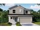 Charming two-story home with gray siding, stone accents, manicured lawn, and a two-car garage at 3824 Bluethread Way, Poinciana, FL 34759