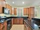 Well-lit kitchen features wooden cabinets, black appliances and granite countertops at 4469 Biscayne Breeze Way, Kissimmee, FL 34744