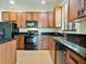 Close-up of a kitchen featuring wood cabinets, black appliances, granite countertops, and tile flooring at 4469 Biscayne Breeze Way, Kissimmee, FL 34744