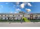 Street view showcasing modern townhomes with well-maintained lawns under a bright blue sky with scattered clouds at 4830 Prairie Preserve Run, St Cloud, FL 34772
