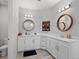 Modern bathroom featuring dual sinks with wood-framed mirrors, and updated lighting fixtures at 675 Primrose Willow Way, Apopka, FL 32712