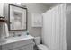 Bathroom features a mirror, white shower curtain, toilet, and vanity with a sink and storage at 675 Primrose Willow Way, Apopka, FL 32712
