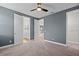 Neutral toned bedroom with carpet, ceiling fan and two white doors leading to the bathroom and hallway at 675 Primrose Willow Way, Apopka, FL 32712