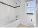 Bright bathroom with white tile walls, a tub, shower, and a window for natural light at 683 Campo Ln, Davenport, FL 33837
