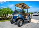A stylish blue and tan golf cart with a sunshade, perfect for community transport at 743 Driving Range Ct, Reunion, FL 34747