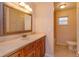 Bathroom featuring light marble countertops, warm cabinetry, and a large mirror at 9681 Lake Douglas Pl, Orlando, FL 32817
