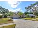 Well-maintained single-story home with a spacious driveway, lush lawn and mature trees at 9681 Lake Douglas Pl, Orlando, FL 32817