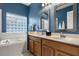 Bathroom featuring a glass block window, soaking tub, and double vanity at 10166 Hidden Dunes Ln, Orlando, FL 32832