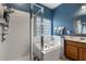 Well-lit bathroom featuring a separate shower, soaking tub, and blue accent wall at 10166 Hidden Dunes Ln, Orlando, FL 32832