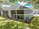 Back of building with screened in patios and lush green lawn and mature shade trees at 130 Lewfield Cir # 130, Winter Park, FL 32792