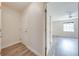 Bright hallway featuring wood-look flooring, white walls, and view into adjacent bedroom at 130 Lewfield Cir # 130, Winter Park, FL 32792