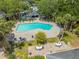 Aerial shot of a refreshing community pool area featuring palm trees and tables with umbrellas at 130 Lewfield Cir # 130, Winter Park, FL 32792