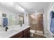 Bright bathroom showcasing double vanity, large mirror, and a tiled glass-enclosed shower at 14743 Driftwater Dr, Winter Garden, FL 34787