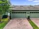 Two-car garages boast matching green doors and are accessed by a red brick driveway at 14743 Driftwater Dr, Winter Garden, FL 34787