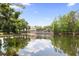 Relaxing view of a community pool with seating area overlooking a pond, surrounded by mature trees at 14743 Driftwater Dr, Winter Garden, FL 34787