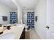 Clean bathroom featuring double sinks, large mirror, granite countertop, and shower with colorful shower curtain at 1706 Leatherback Ln, St Cloud, FL 34771