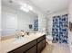 Bathroom featuring double sinks, large mirror, granite countertop, and shower with colorful shower curtain at 1706 Leatherback Ln, St Cloud, FL 34771