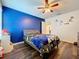 Bedroom with blue accent wall, wood floors, and floating shelves at 1706 Leatherback Ln, St Cloud, FL 34771