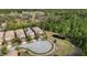 An aerial view of homes with tile roofs and solar panels surrounding a pond and wooded area at 1801 Nice Ct, Kissimmee, FL 34747