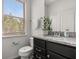 This half-bathroom offers a granite vanity, toilet, mirror, and a large window for lots of light at 1801 Nice Ct, Kissimmee, FL 34747
