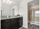 Bathroom featuring dual sinks, dark cabinets and a glass shower with tile surround at 1801 Nice Ct, Kissimmee, FL 34747
