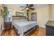 Bright main bedroom with light yellow walls, hardwood floors, fan, and a glimpse of the en-suite bathroom at 208 Madeira Ave, Orlando, FL 32825