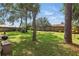 Spacious backyard with mature trees and lawn, enclosed by a wooden fence for privacy at 2277 Clearwater Dr, Deltona, FL 32738