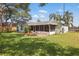 Spacious backyard featuring a screened patio, lush lawn, and mature trees on a sunny day at 2277 Clearwater Dr, Deltona, FL 32738