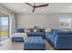 Comfortable living room featuring a plush blue sectional sofa, ottoman, ceiling fan, and sliding glass door to the backyard at 2515 W End Dr, St Cloud, FL 34772
