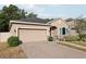 Inviting single-story home featuring a brick driveway, two-car garage, stone accents and manicured landscaping at 34423 Alameda Dr, Sorrento, FL 32776