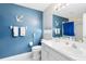 Nautical-themed bathroom with blue accent wall, white fixtures, and anchor decorations at 3661 Kingswood Ct, Clermont, FL 34711