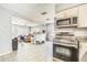 Kitchen with gray tile, appliances and cabinetry leading into another room at 409 Lake Ned Rd, Winter Haven, FL 33884