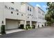 Exterior view of townhomes with attached garages, beige stucco and well-maintained landscaping at 4725 Anson Ln, Orlando, FL 32814