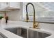 Close-up of a modern kitchen sink with a brushed gold faucet and quartz countertops next to bright window at 507 Peach Tree Ln, Altamonte Springs, FL 32701