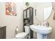 Half bathroom with pedestal sink, round mirror and cabinet with glass doors above the toilet at 525 Narrow View Ln, Groveland, FL 34736