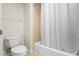 Toilet and bathtub features a white shower curtain and tiled wall in bathroom at 7689 Heritage Crossing Way # 202, Reunion, FL 34747