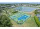 Aerial view of community amenities featuring a lake, basketball court, and tennis court surrounded by tropical landscaping at 833 Lockbreeze Dr, Davenport, FL 33897