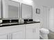 Modern bathroom with double sinks, sleek black countertops, and white cabinetry at 833 Lockbreeze Dr, Davenport, FL 33897