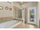 A bathroom featuring a bathtub, a glass-enclosed shower, and access to a screened outdoor pool at 8804 Rhodes Street, Kissimmee, FL 34747
