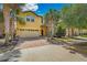 Two-story home with a two-car garage, brick driveway, stone accents, and lush landscaping with palm trees at 8804 Rhodes Street, Kissimmee, FL 34747