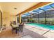 A covered patio featuring an outdoor dining area overlooking the screened swimming pool and landscaped backyard at 8804 Rhodes Street, Kissimmee, FL 34747