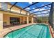 A screened outdoor pool with a patio featuring a dining table and chairs, and a grilling area at 8804 Rhodes Street, Kissimmee, FL 34747
