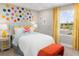 Colorful bedroom with polka dot wall, yellow accents, and view through the window at 9980 Red Canoe Aly, Orlando, FL 32832